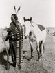 Sioux Indian full-length portrait poster print featuring a warrior holding a rifle in front of a horse.