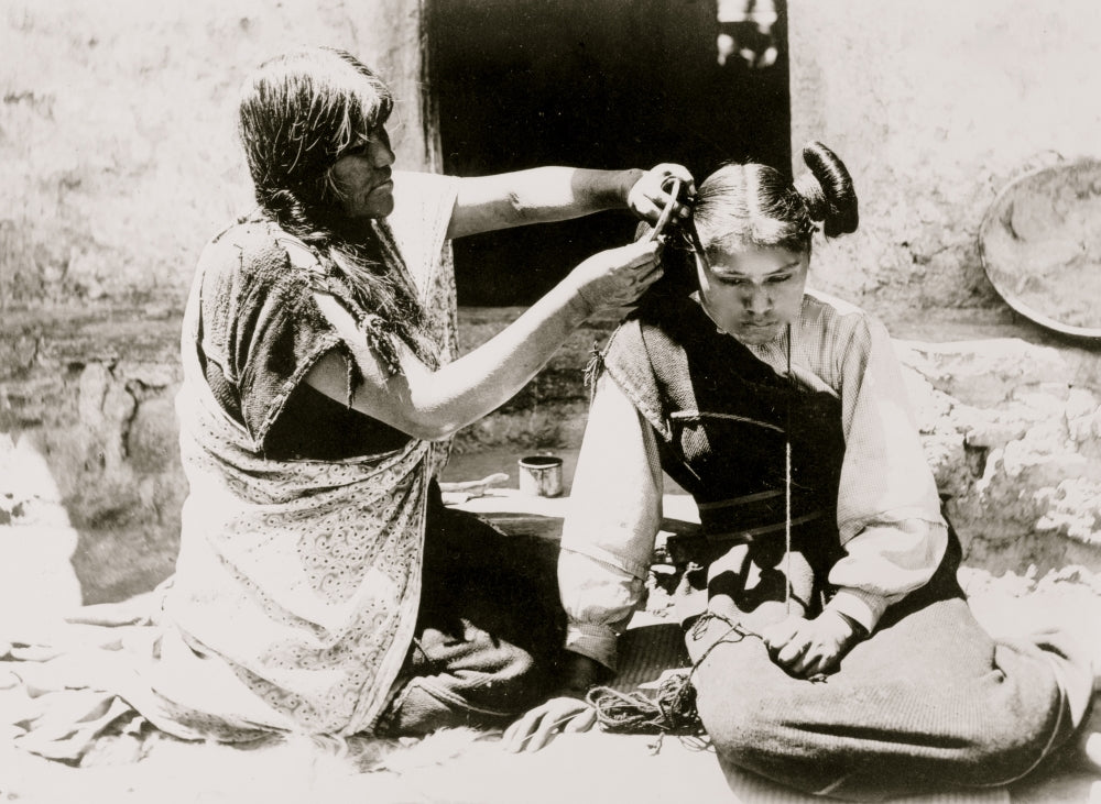 Kneeling Hopi woman combing hair of young girl poster print.