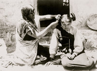 Kneeling Hopi woman combing hair of young girl poster print.