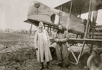Capt. Berthaut and Capt. Hoppe in front of a German bi-plane poster print.