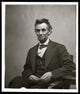 Abraham Lincoln three-quarter length portrait poster print showing him seated with spectacles and pencil.