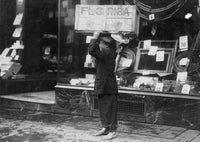Scavenger holding a box of wood in front of a retail establishment poster print.