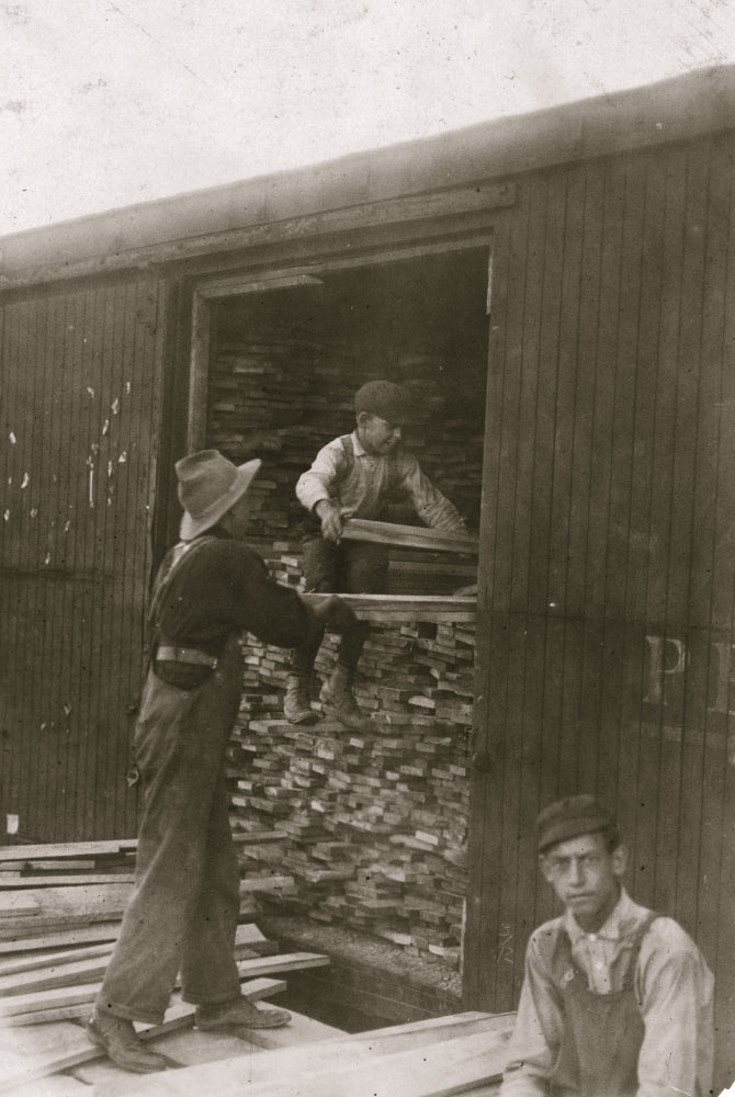 Young boy unloading wood from a boxcar poster print
