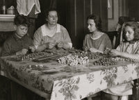 Cottage Industry Poster Print depicting a family stringing material in piecework at home.