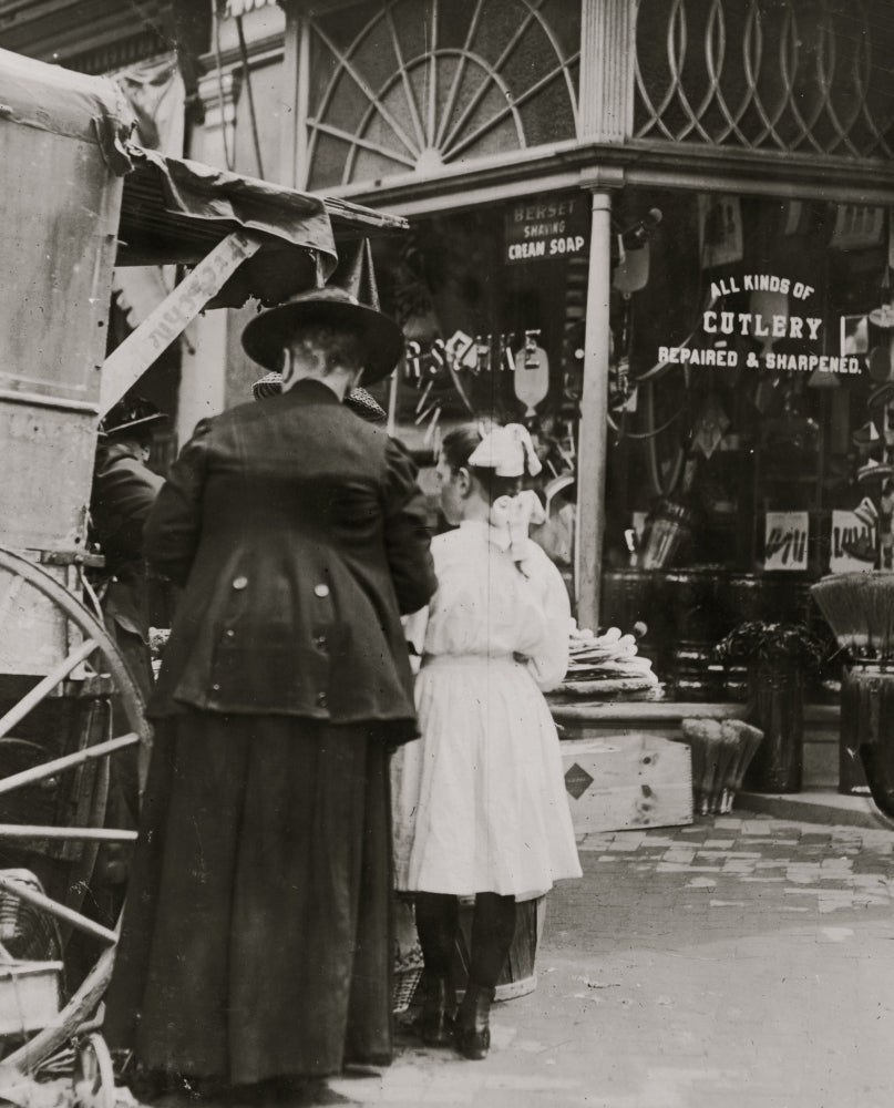 Young vendor sells goods outside a cutlery store poster print.