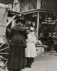 Young vendor sells goods outside a cutlery store poster print.