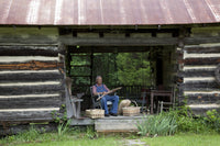 Basket Weaver in Log Cabin Poster Print showcasing traditional craftsmanship