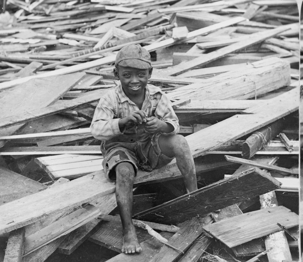 Poster print of an African American boy sitting on debris after the 1900 hurricane in Galveston, Texas.