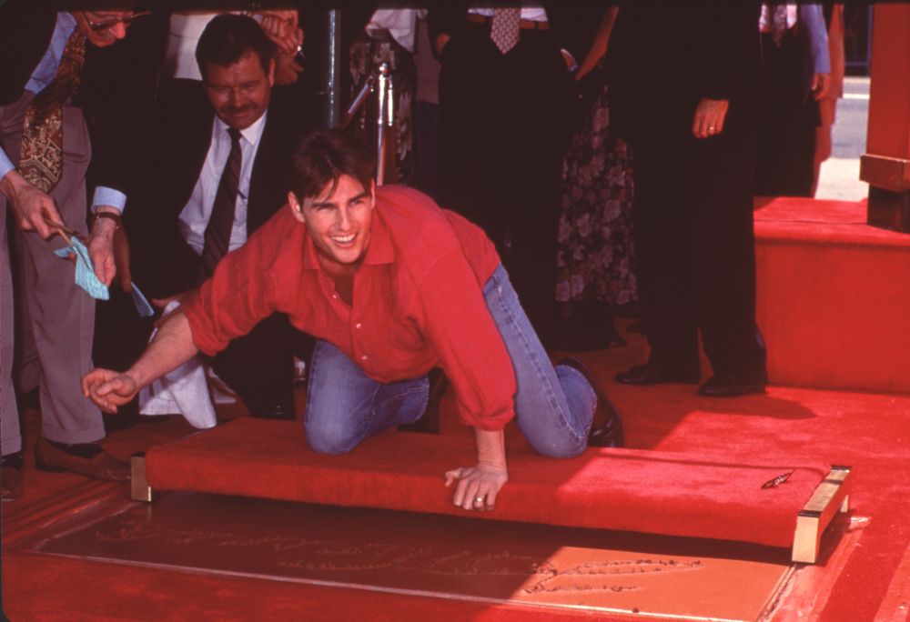 Tom Cruise leaning over his hand and footprints photo print.
