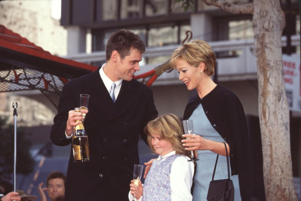 Photo print of Jim Carrey, Lauren Holly, and daughter Jane with champagne glasses.
