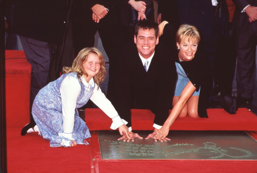 Jane Carrey and Lauren Holly pushing Jim Carrey's hands into cement photo print.