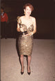 Melanie Mayron holding an award in a strapless gold dress photo print