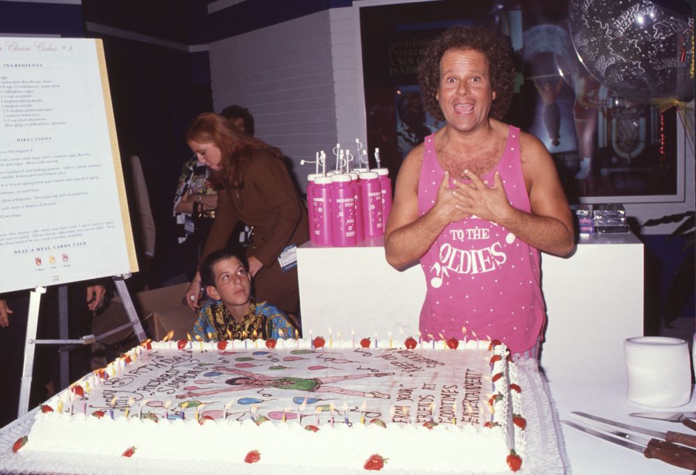 Richard Simmons photo print over cake in pink tank top.