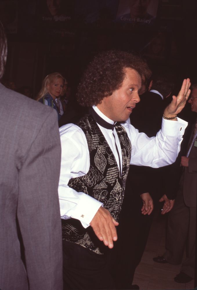 Richard Simmons dancing in dress shirt with gold and black vest photo print.