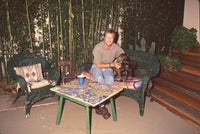 Brad Maule sitting on wicker couch with black dog photo print
