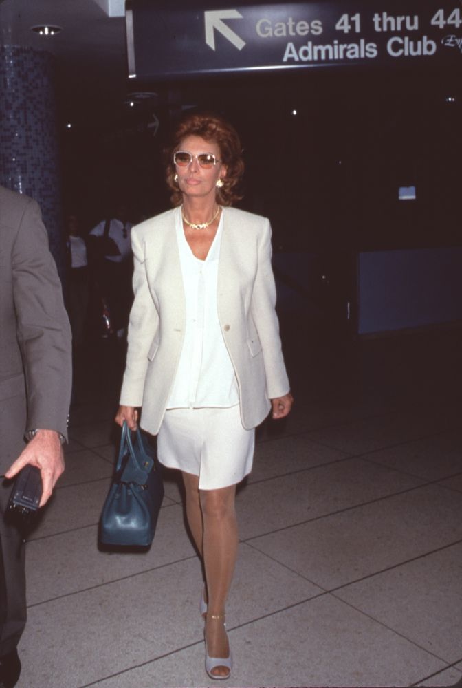 Sophia Loren walking through airport in elegant white suit photo print