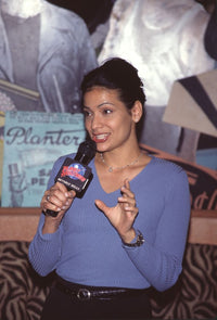 Constance Marie in a blue long sleeve top holding a microphone, photo print.
