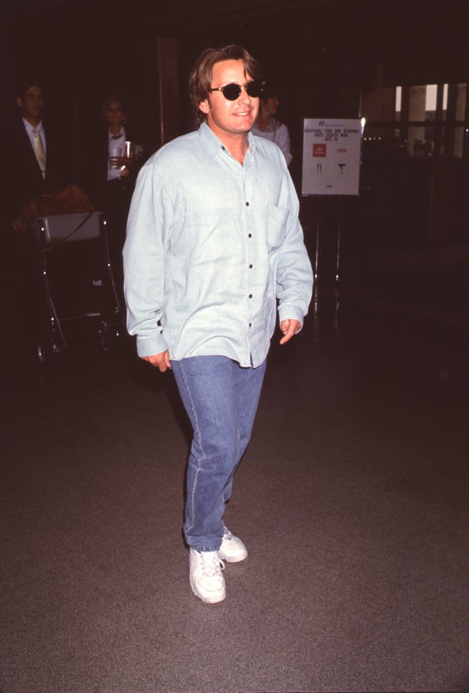Emilio Estevez stylish photo print at LAX, wearing jeans and sunglasses.