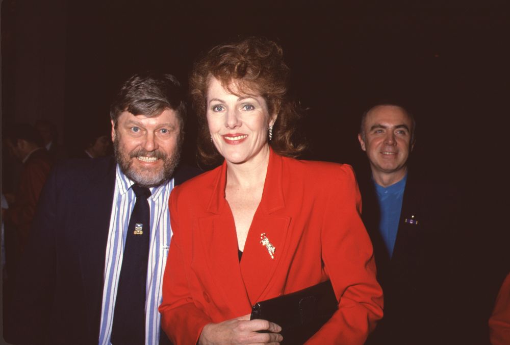 Lynn Redgrave in red jacket with John Clark in suit and blue striped shirt photo print.