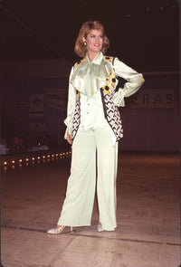 Mary Hart in light green outfit with sunflower vest at fashion show.