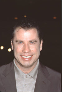 Close-up photo print of John Travolta at Primary Colors premiere, dressed in a brown suit and tan shirt.