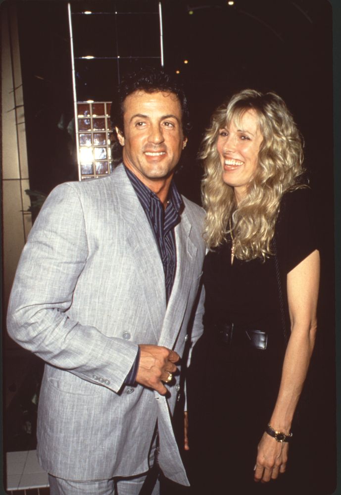 Sylvester Stallone in gray suit and Alana Stewart in black outfit with belt photo print