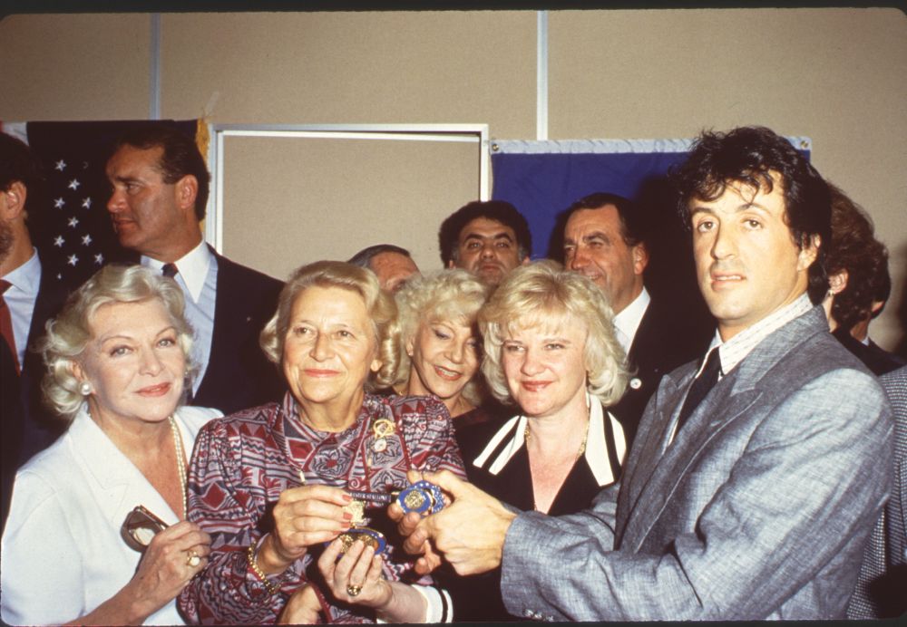 Sylvester Stallone in gray suit with older women photo print.