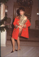 Colleen Dion photo print in red and gold outfit with off-shoulder jacket.