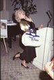Phyllis Diller photo print in black dress with gold sleeves holding duffle bag