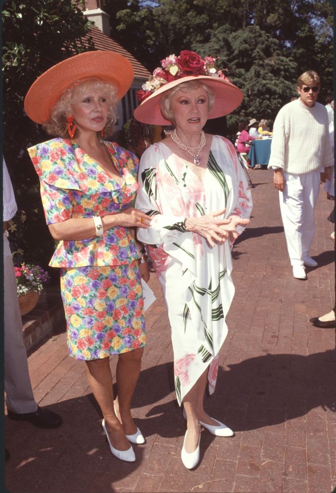 Josette Banzet in floral skirt suit and orange hat with Phyllis Diller in white dress with pink flowers and pink hat photo print.