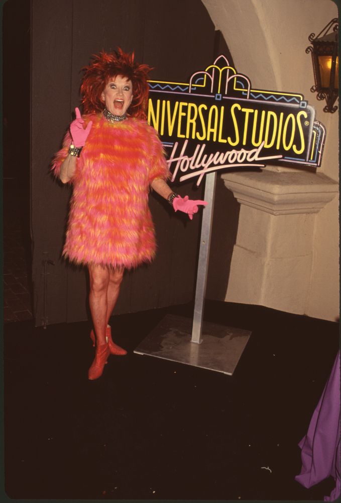 Phyllis Diller in orange and pink fur next to Universal Studios Hollywood sign photo print.