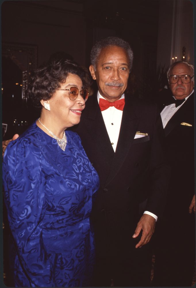 Joyce Dinkins in blue long sleeve dress with David Dinkins in tuxedo and red bowtie photo print.