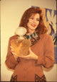 Priscilla Presley photo print in tan blazer holding perfume bottle