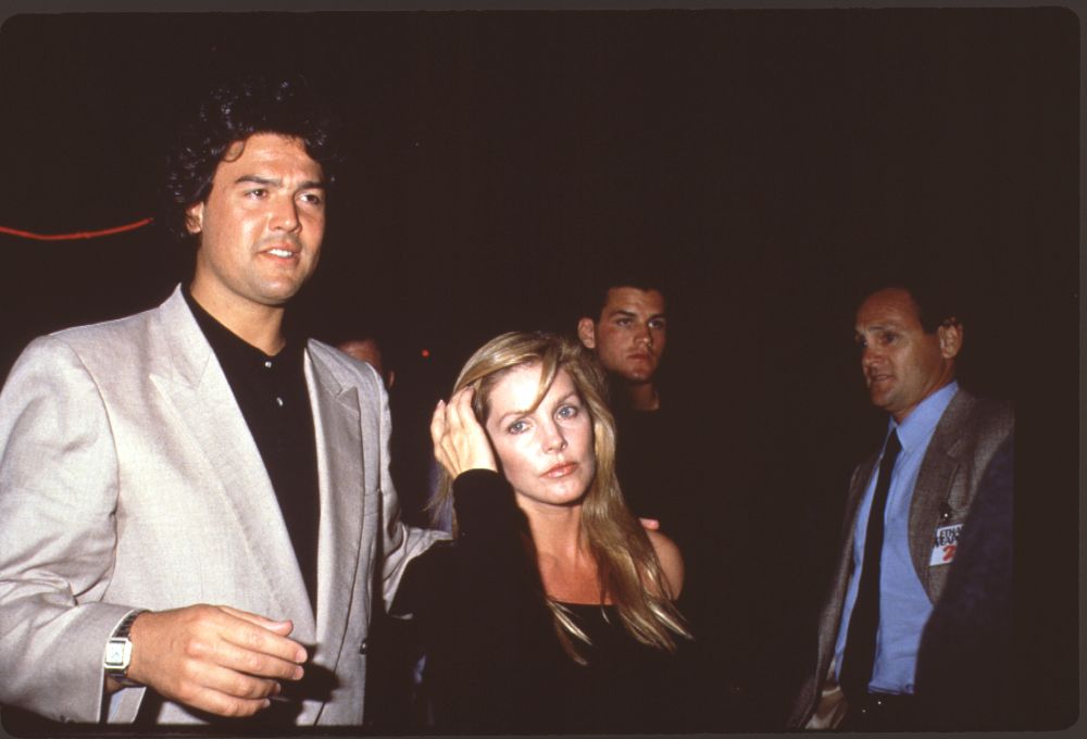 Marco Garibaldi in gray blazer with Priscilla Presley in black off-shoulder top photo print.