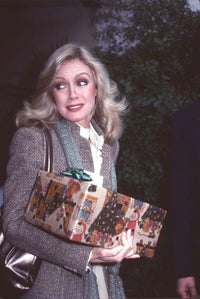 Donna Mills carrying a present in a gray blazer photo print