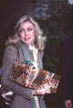 Donna Mills carrying a present in a gray blazer photo print