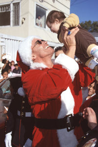 Arnold Schwarzenegger dressed as Santa holding a baby photo print
