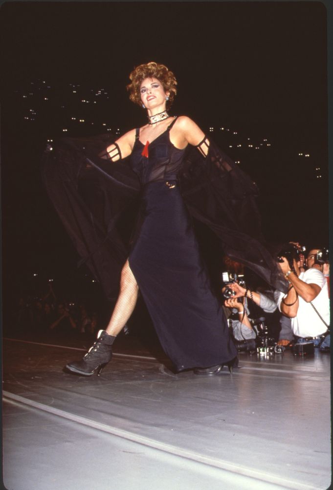 Raquel Welch on stage in black gown with sheer cape photo print
