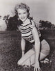 Anne Francis Kneeling in Grass Photo Print showcasing classic Hollywood beauty.