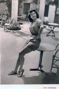 Ava Gardner Sitting on Table Photo Print capturing classic Hollywood elegance.
