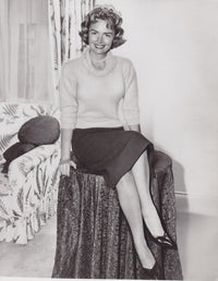 Donna Reed posed on table photo print, vintage Hollywood elegance.