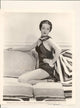 Dorothy Lamour photo print kneeling on couch with hand on hip.