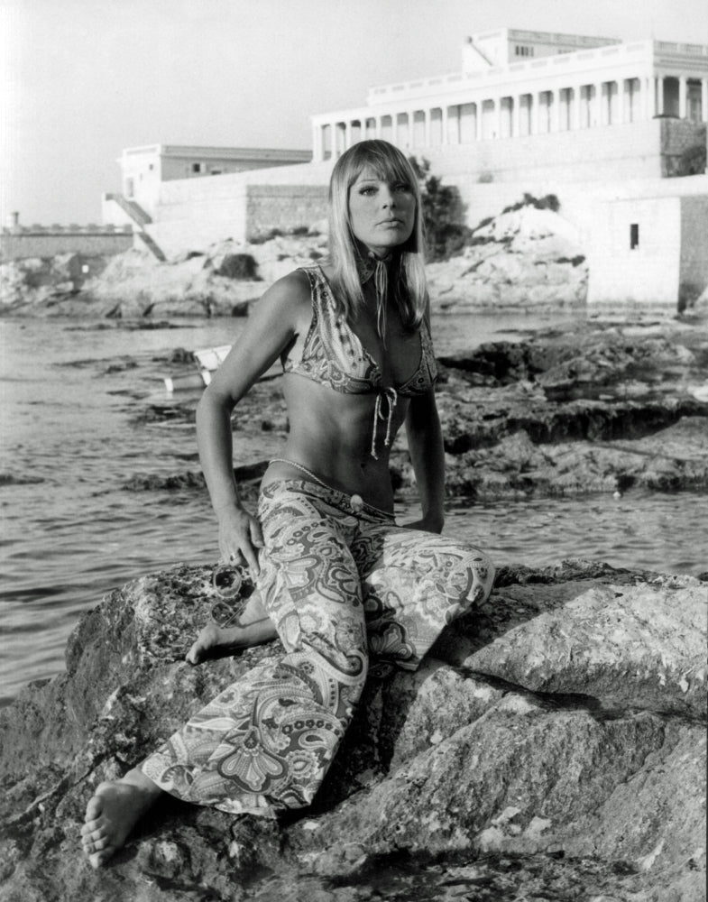 Elke Sommer sitting on rocks wearing patterned pants and bra photo print.