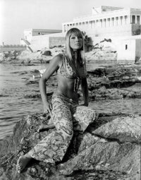 Elke Sommer sitting on rocks wearing patterned pants and bra photo print.