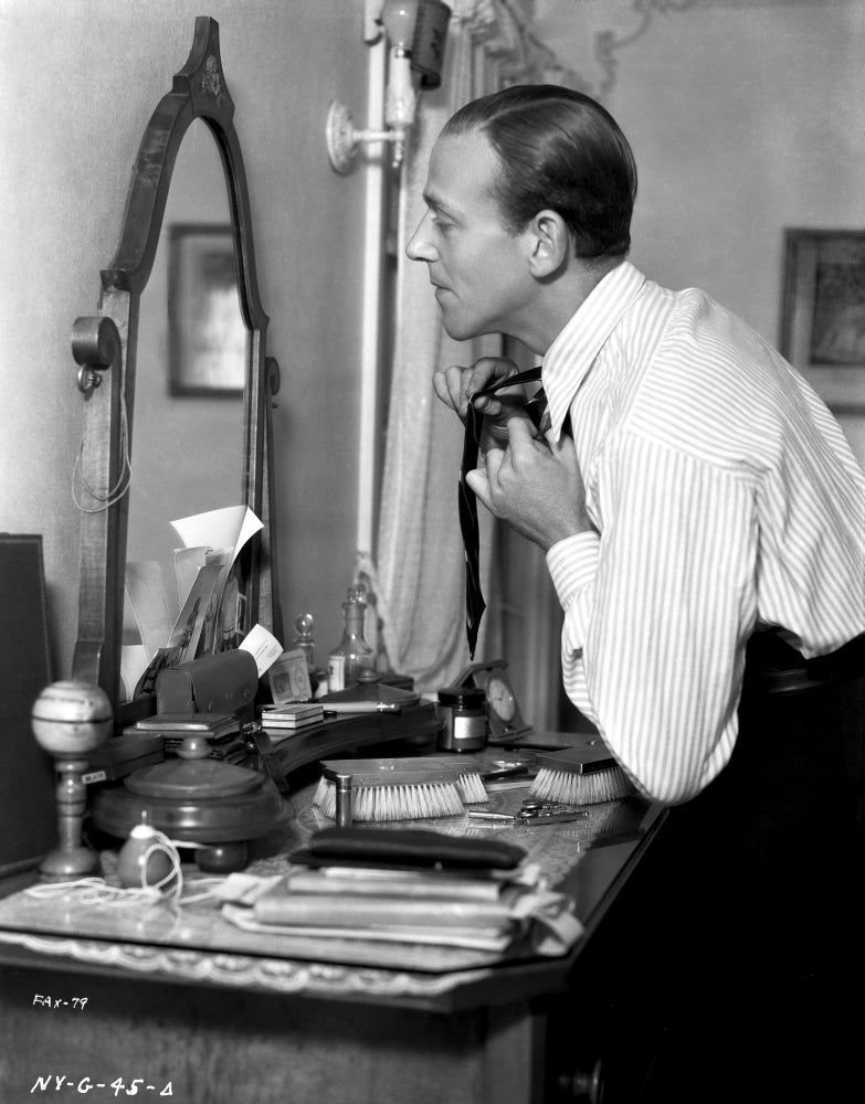 Fred Astaire fixing his tie in a classic black and white photo print.