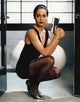 Yancy Butler sitting pose portrait in black dress with pistol, photo print.