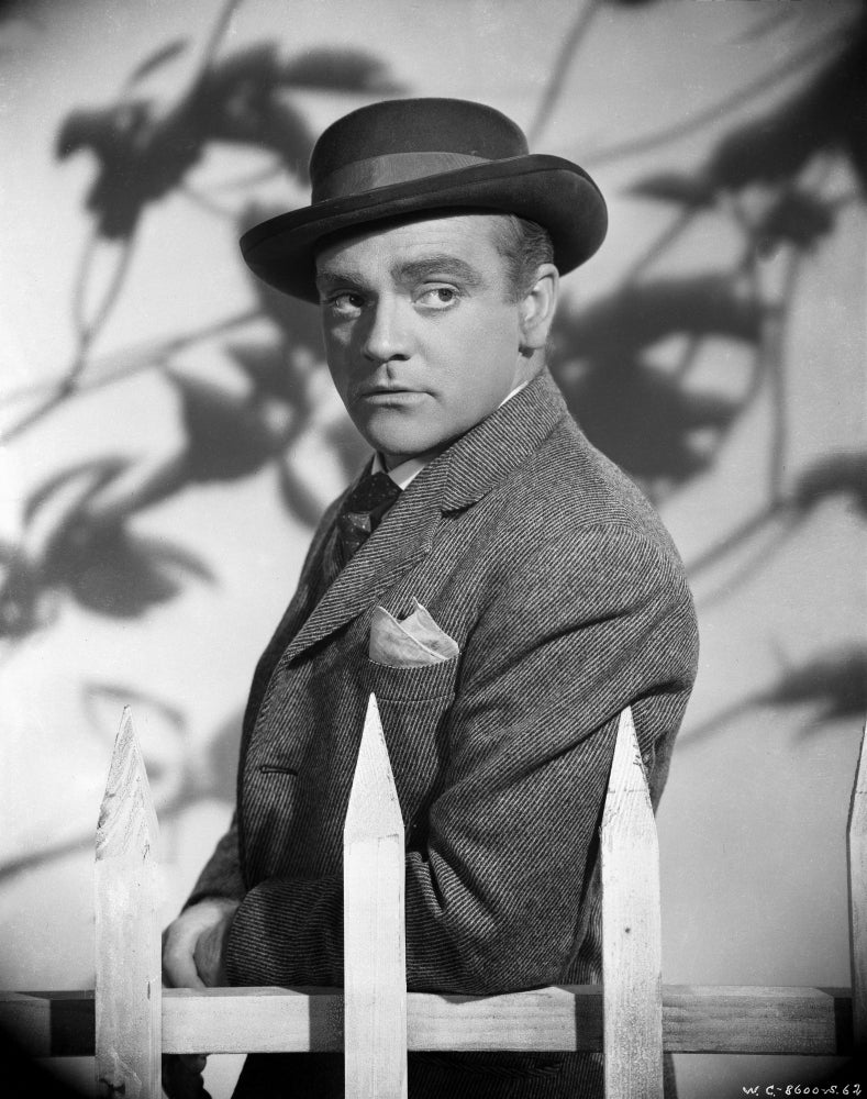 James Cagney photo print in grey linen suit standing by a wood fence.