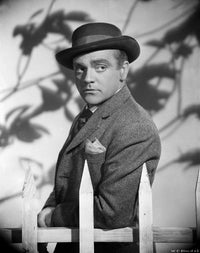 James Cagney photo print in grey linen suit standing by a wood fence.