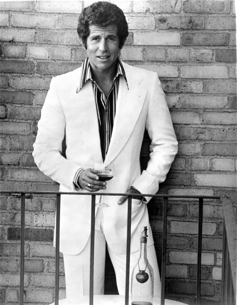 Tony Roberts Photo Print wearing a suit in front of a brick wall.