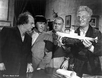 Film still of Emil Stika carrying a model ship photo print.